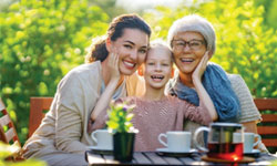 Three generations of women enjoy an outdoor tea party on a sunny day. They are confident that their future is financially secure with the Single Premium Whole Life Insurance they have purchased.