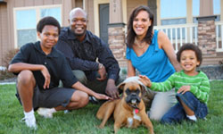 A mom, dad, and 2 children relax in their yard with their brown dog, all feeling confident that their financial futures are secure thanks to their term life insurance.