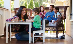 A family of five relaxes on the porch on a summer day, enjoying the peace of mind that comes with protecting their secure financial future with term life insurance for the children.