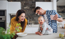 A young couple gazes at their adorable baby in the kitchen, knowing their term life insurance is protecting her future financial security. A young couple gazes at their adorable baby in the kitchen, knowing their term life insurance is protecting her future financial security.