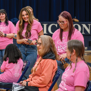 Group of women and girls sitting on chairs cut hair for cancer
